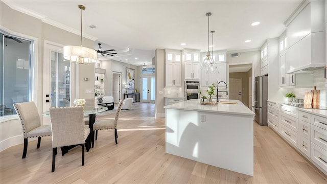 kitchen featuring visible vents, a kitchen island with sink, custom exhaust hood, stainless steel appliances, and a sink