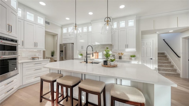 kitchen featuring appliances with stainless steel finishes, light countertops, a sink, and an island with sink