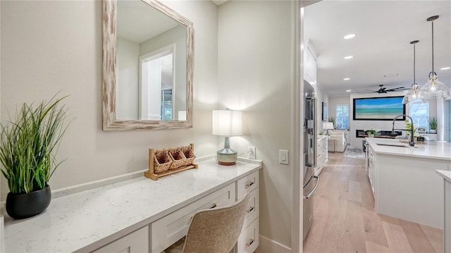 hall featuring light wood-type flooring, a sink, and recessed lighting