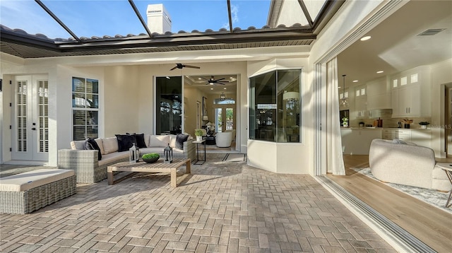 view of patio featuring visible vents, glass enclosure, ceiling fan, french doors, and outdoor lounge area