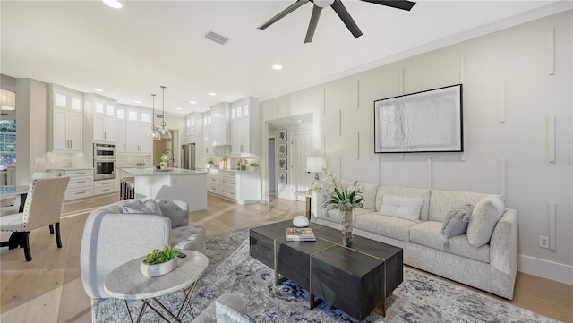 living area featuring a ceiling fan, light wood-type flooring, visible vents, and recessed lighting