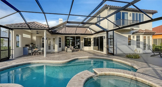 rear view of property with french doors, a tile roof, a patio, a pool with connected hot tub, and a balcony