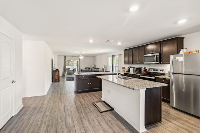 kitchen featuring visible vents, appliances with stainless steel finishes, open floor plan, light wood-style floors, and a sink