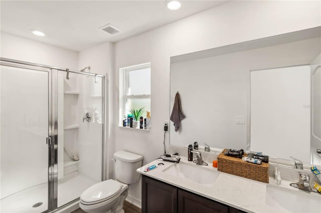 bathroom featuring toilet, a stall shower, a sink, and visible vents