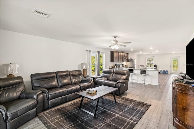 living room with ceiling fan, light wood finished floors, visible vents, and recessed lighting