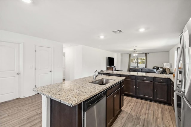 kitchen featuring stainless steel appliances, visible vents, light wood-style floors, a sink, and dark brown cabinetry