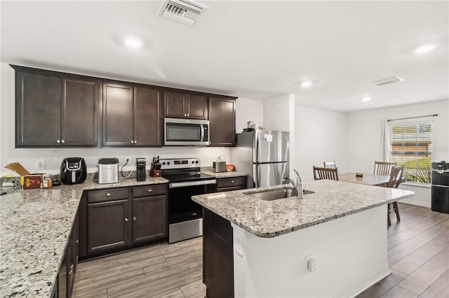 kitchen with appliances with stainless steel finishes, visible vents, a sink, and light wood-style flooring