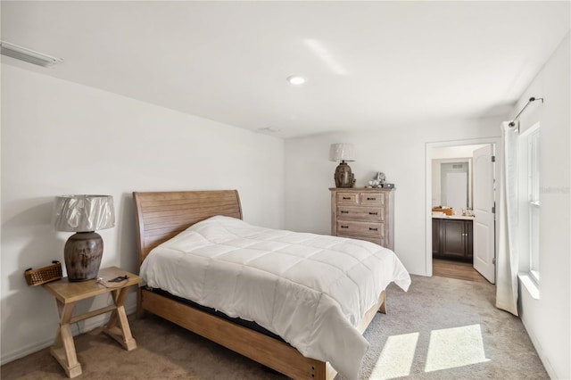 bedroom featuring light carpet, baseboards, visible vents, and connected bathroom