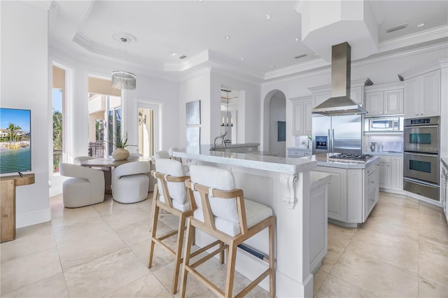 3935 N Shell Rd, Sarasota, FL 34242 - kitchen with stainless steel appliances, a kitchen island with sink, island range hood, a warming drawer, and ornamental molding