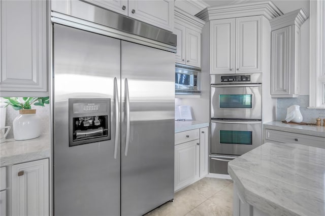 3935 N Shell Rd, Sarasota, FL 34242 - kitchen with appliances with stainless steel finishes, white cabinetry, a warming drawer, backsplash, and light stone counters