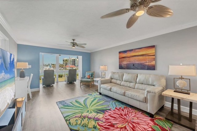 living room featuring ceiling fan, crown molding, baseboards, and wood finished floors