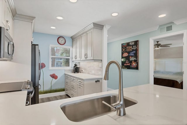 kitchen with tasteful backsplash, visible vents, ornamental molding, stainless steel appliances, and a sink