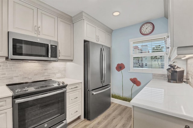 kitchen with stainless steel appliances, white cabinets, light countertops, and backsplash