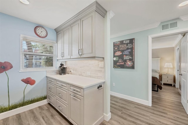 kitchen featuring light countertops, backsplash, visible vents, and light wood-style floors