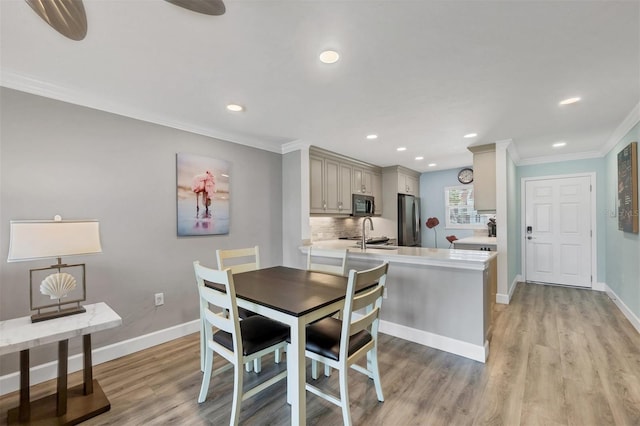 dining space featuring ornamental molding, light wood-type flooring, recessed lighting, and baseboards