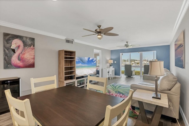 dining room with beverage cooler, ornamental molding, wood finished floors, and visible vents