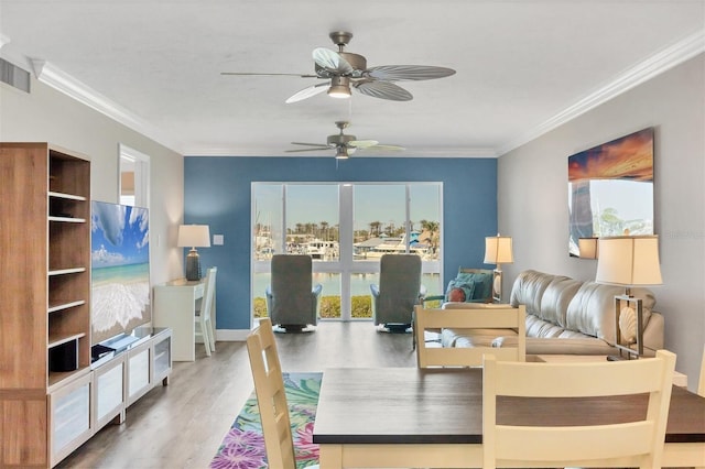 living area with baseboards, wood finished floors, visible vents, and crown molding