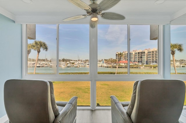 sunroom featuring a water view and a ceiling fan