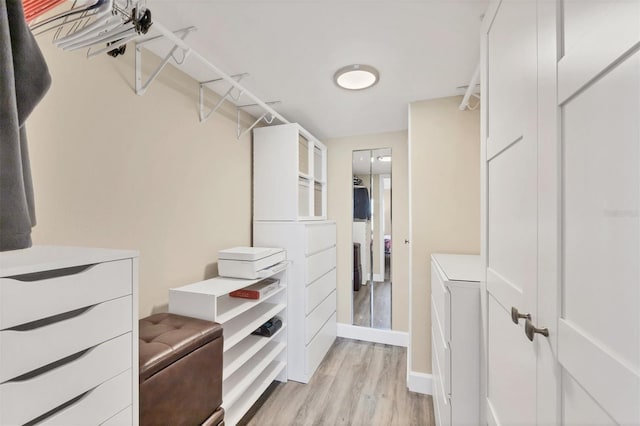 walk in closet with light wood-style floors and washer / dryer