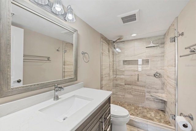 bathroom featuring toilet, a stall shower, vanity, and visible vents