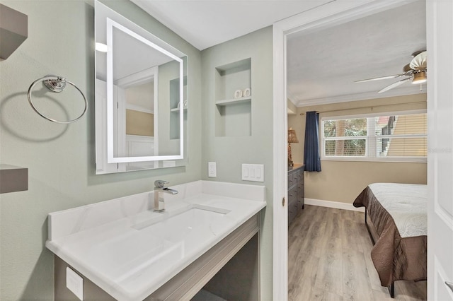 ensuite bathroom with baseboards, ensuite bath, ceiling fan, wood finished floors, and vanity