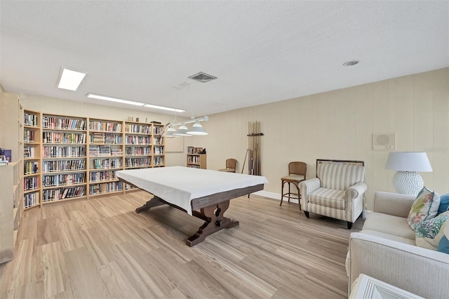 recreation room featuring a textured ceiling, visible vents, and wood finished floors