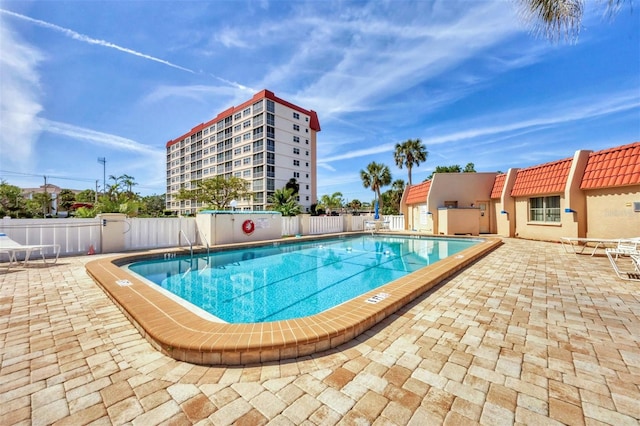 pool with a patio area and fence