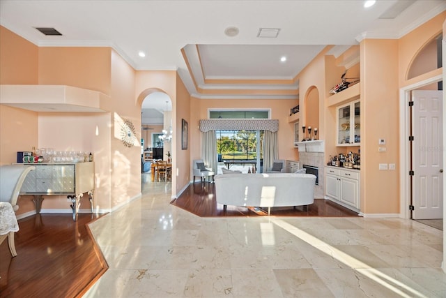 foyer with a bar, marble finish floor, baseboards, and crown molding