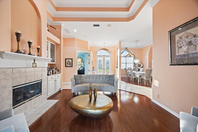 living room with dark wood-style floors, crown molding, a fireplace, visible vents, and baseboards