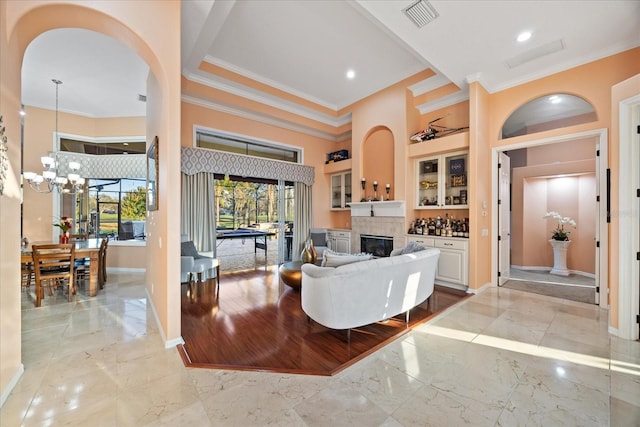 living room with marble finish floor, baseboards, built in features, and a glass covered fireplace