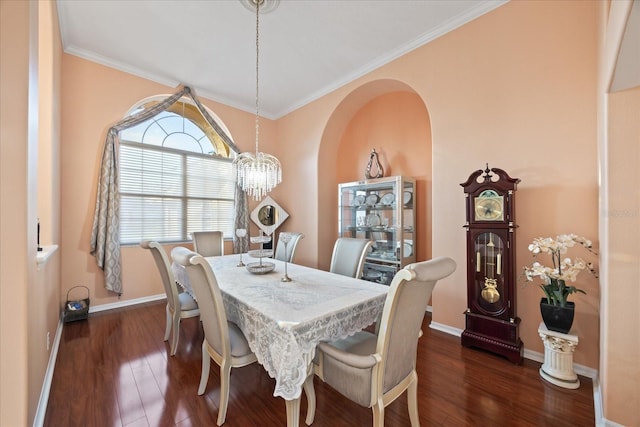 dining room featuring arched walkways, a chandelier, dark wood finished floors, and baseboards