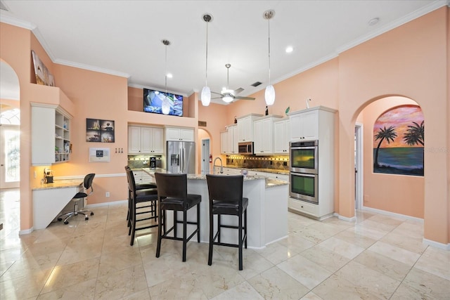 kitchen featuring a high ceiling, appliances with stainless steel finishes, backsplash, and crown molding