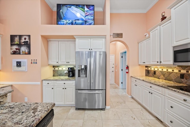 kitchen featuring arched walkways, white cabinets, appliances with stainless steel finishes, ornamental molding, and marble finish floor