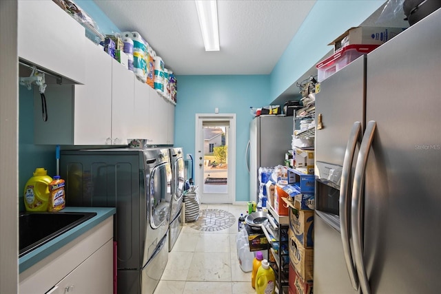 laundry area with washing machine and dryer, cabinet space, a sink, and a textured ceiling