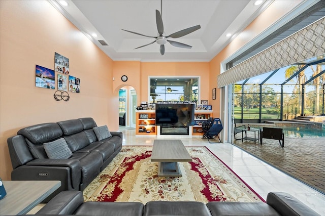 tiled living area with a tray ceiling, recessed lighting, a high ceiling, a sunroom, and ceiling fan