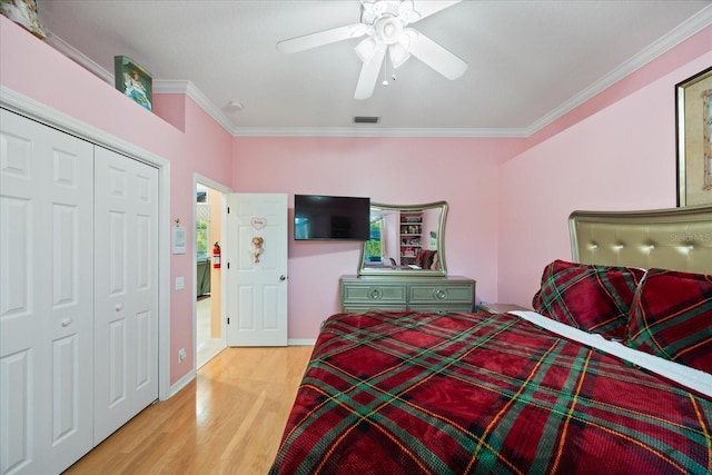 bedroom with crown molding, a closet, visible vents, light wood-style flooring, and ceiling fan