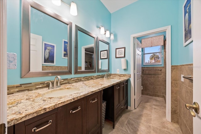 bathroom with double vanity, a sink, toilet, and tile walls