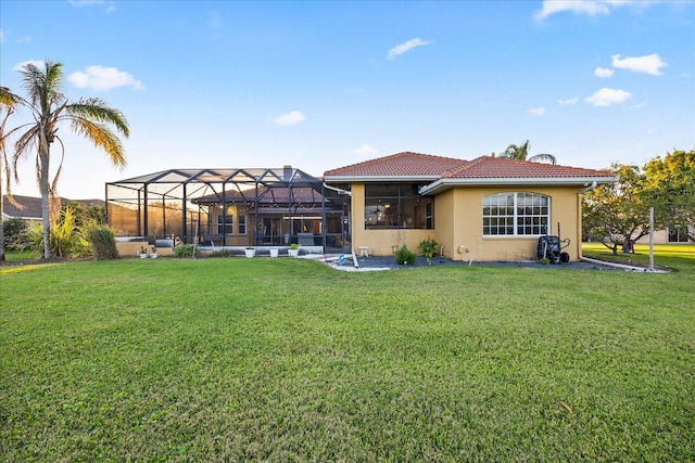 rear view of property with a lanai, a lawn, and stucco siding