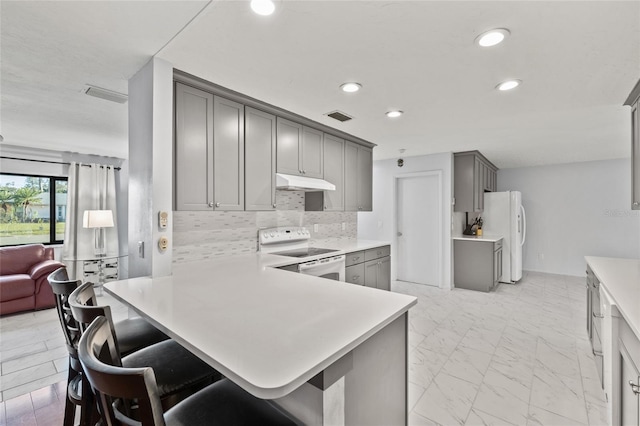 kitchen with white appliances, under cabinet range hood, gray cabinetry, and marble finish floor