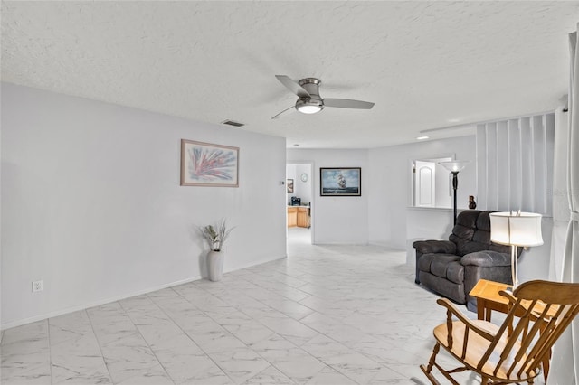 living area with marble finish floor, ceiling fan, visible vents, and baseboards