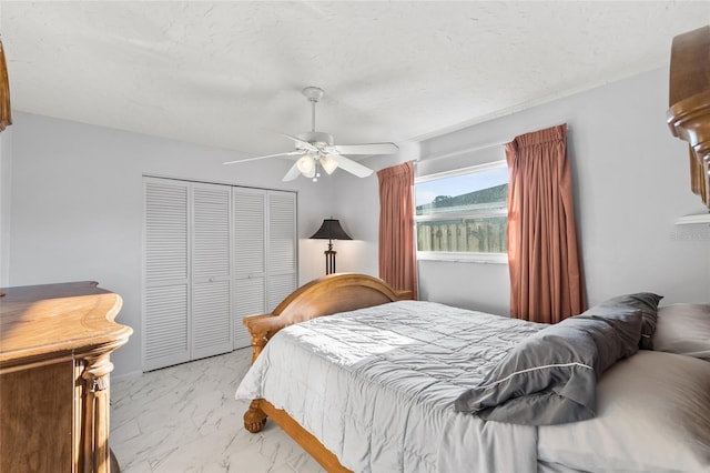 bedroom with a closet, marble finish floor, ceiling fan, and a textured ceiling