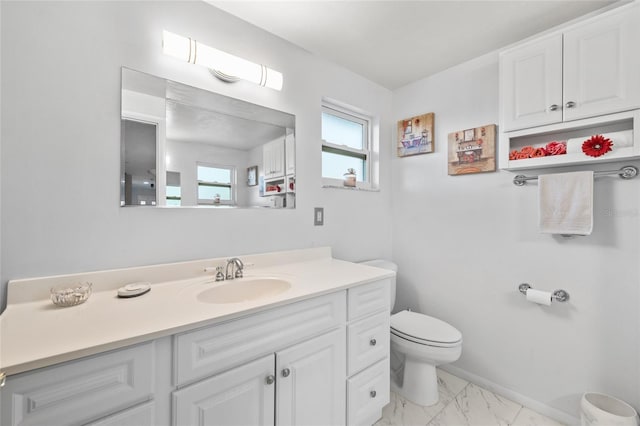 bathroom with marble finish floor, vanity, toilet, and baseboards