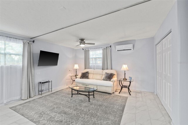 living area with marble finish floor, ceiling fan, baseboards, and a wall mounted AC