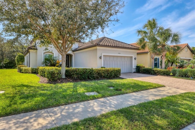 mediterranean / spanish house featuring an attached garage, driveway, a tiled roof, stucco siding, and a front yard