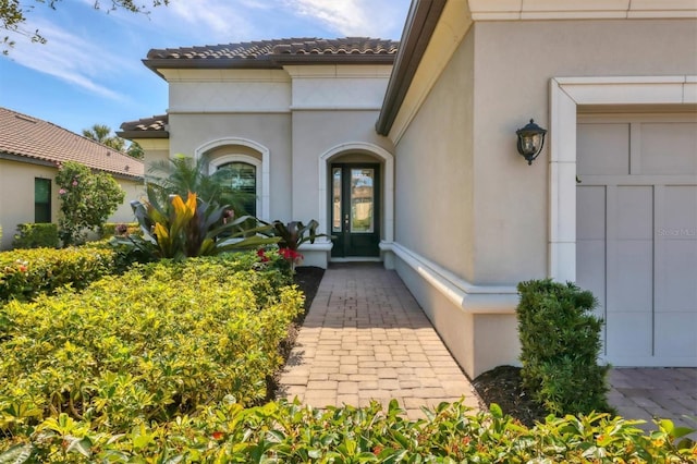 view of exterior entry with a tile roof and stucco siding