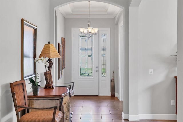 entryway with arched walkways, a notable chandelier, baseboards, ornamental molding, and a tray ceiling