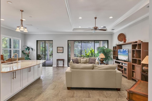 living area with a tray ceiling, recessed lighting, ornamental molding, ceiling fan, and baseboards