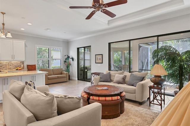 living room with light tile patterned flooring, recessed lighting, a ceiling fan, ornamental molding, and a raised ceiling