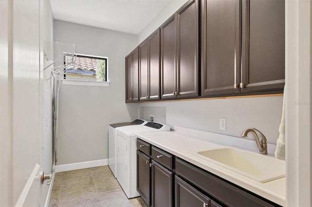 clothes washing area featuring washer and dryer, cabinet space, a sink, and baseboards