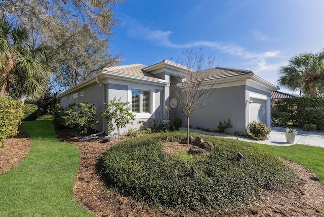 view of front of home with an attached garage, a tile roof, and stucco siding